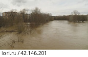 Flooding. A brown, muddy river. A fast-flowing stream after heavy rain. A dangerous river, carrying rubbish and mud. The building in the background and the grey sky. An environmental disaster. Стоковое видео, видеограф Воловодов Владимир / Фотобанк Лори