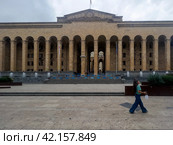 A girl walks along Shota Rustaveli Avenue past the Georgian Parliament building. Tbilisi. Georgia. 03.09.2023. Редакционное фото, фотограф Ярославский Максим / Фотобанк Лори