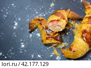 Sliced baked pastry with ham and cheese on a dark background, dusted with a powdery substance, homemade croissant stuffed and cut in half. Стоковое фото, фотограф carlos l vives / Фотобанк Лори