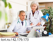 Two doctors working with patient records on laptop in medical office. Стоковое фото, фотограф Яков Филимонов / Фотобанк Лори