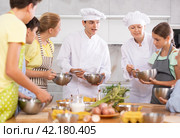 During cooking lesson, male cook tells children about culinary rules, woman assistant helps child. Стоковое фото, фотограф Яков Филимонов / Фотобанк Лори