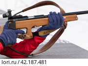 Sportswoman biathlete rifle shooting in prone position in shooting range. Selective focus, extreme close-up shot (2019 год). Редакционное фото, фотограф А. А. Пирагис / Фотобанк Лори