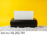 Office paper shredder on yellow studio background. Стоковое фото, фотограф Сергей Толмачёв / Фотобанк Лори