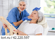 Mature patient with mirror, doctor with gloves. Стоковое фото, фотограф Яков Филимонов / Фотобанк Лори