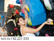 Female fitness climber training at bouldering gym. Young woman rise up on artificial climbing wall. Стоковое фото, фотограф Яков Филимонов / Фотобанк Лори