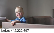Baby in the crib looks around and smiles. Стоковое видео, видеограф Ekaterina Demidova / Фотобанк Лори