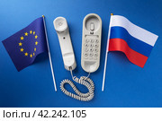 Flag of the European Union, Russia and an old corded telephone on a blue background, concept on the topic of telephone conversations. Стоковое фото, фотограф Сергей Чайко / Фотобанк Лори