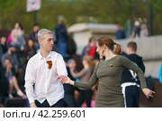 Moscow, Russia - May 9, 2022: Cheerful Dancing couple of young man and woman in public park. Lifestyle theme. Having fun people. People celevrate Victory Day, the win in the Great Patriotic War. Редакционное фото, фотограф YuryKara / Фотобанк Лори
