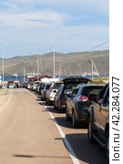BAIKAL LAKE, SAKHYURTA VILLAGE, IRKUTSK REGION, RUSSIA - August 14, 2023: Traditional summer queue of tourist cars for the ferry crossing to Olkhon Island - popular holiday destination. Редакционное фото, фотограф Виктория Катьянова / Фотобанк Лори