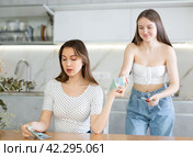 Young woman giving money to her sister in kitchen. Стоковое фото, фотограф Яков Филимонов / Фотобанк Лори