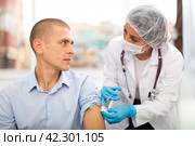 Doctor in a protective mask injects a vaccine to a man with syringe. Стоковое фото, фотограф Яков Филимонов / Фотобанк Лори