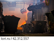 Производство меди на металлургическом заводе. Расплавленный металл льется из огромной ёмкости. Крупные промышленные сооружения, мостовые краны и дым. Медный завод, Норильск, Красноярский край, Россия. Редакционное фото, фотограф Андрей Степанов / Фотобанк Лори