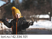 Portrait of a little boy in a yellow hat. The child runs through puddles on the farm, has fun and plays. It's a sunny day. Early spring. The first drop. Стоковое фото, фотограф Photojuli / Фотобанк Лори