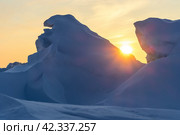 Зимний арктический пейзаж. Вид на большие ледяные торосы и сугробы. Восход солнца над замерзшим морем. Холодная морозная зимняя погода. Суровый климат полярного региона. Солнце над заснеженными льдинами. Стоковое фото, фотограф Андрей Степанов / Фотобанк Лори