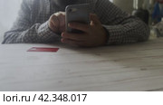 The man sits down at the table and dials the payment cards of his plastic card for an online transaction. Стоковое видео, видеограф Ярославский Максим / Фотобанк Лори