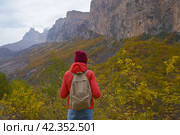 Brunette woman with a backpack on her back outdoors exploring the Caucasus Mountains in Russia, traveling, lifestyle, hiking, active autumn holidays, hiking. Стоковое фото, фотограф Екатерина Золина / Фотобанк Лори