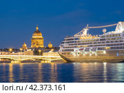 Круизный лайнер Azamara Journey пришвартовался на Английской набережной на фоне Исаакиевского собора в Санкт-Петербурге во время белых ночей (2019 год). Редакционное фото, фотограф Ольга Визави / Фотобанк Лори
