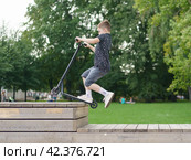 Moscow, Russia - July 26, 2019 Trick at sportive push scooter on a city street. Редакционное фото, фотограф YuryKara / Фотобанк Лори