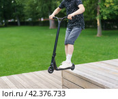 Trick at sportive push scooter in the park. Стоковое фото, фотограф YuryKara / Фотобанк Лори