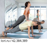 Sports young woman and man doing acrobatics yoga poses, practicing acroyoga at gym. Стоковое фото, фотограф Яков Филимонов / Фотобанк Лори