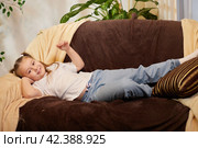 A little girl is relaxing in room on sofa. A schoolgirl is lazy after school. Teen idling or bored at home. Стоковое фото, фотограф Кривошеина Елена Леонидовна / Фотобанк Лори