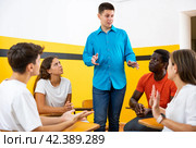 Male student discussing with groupmates sitting in circle in auditorium during classes. Стоковое фото, фотограф Яков Филимонов / Фотобанк Лори