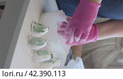 A woman covers a homemade marshmallow with powdered sugar. Tulip buds made of marshmallows with green leaves. Vertical video. Стоковое видео, видеограф Vadzim Yakubovich / Фотобанк Лори