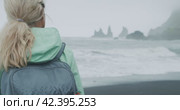 Close up of a woman on black sand beach enjoying view to Reynisfjara sea stack cliff formations, Vik, Iceland. Стоковое видео, видеограф Igor Tichonow / Фотобанк Лори