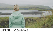 Woman enjoying Iceland Seljalandsfoss waterfall from far distance. Стоковое видео, видеограф Igor Tichonow / Фотобанк Лори