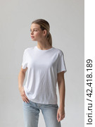 Beautiful blonde woman in a white T-shirt and blue jeans posing on a white background. Стоковое фото, фотограф Женя Канашкин / Фотобанк Лори