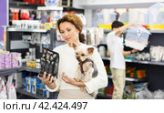 Woman with Yorkshire terrier choosing dry dog food in pet store. Стоковое фото, фотограф Яков Филимонов / Фотобанк Лори