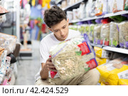Teen boy take hay from shelf in pet store. Стоковое фото, фотограф Яков Филимонов / Фотобанк Лори