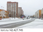 Город Тында, Амурская область, Россия. Улица Красная Пресня. Слева здание администрации города Тынды. Вид на многоэтажные жилые дома. На заснеженной улице скульптурная композиция в виде серпа и молота. Холодная погода. Зима. Редакционное фото, фотограф Андрей Степанов / Фотобанк Лори