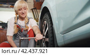 Автосервис. Attractive woman in mechanic uniform working with wheel. Стоковое видео, видеограф EStarodubov / Фотобанк Лори