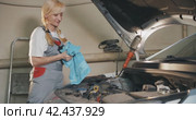 Автосервис. Attractive female mechanic carries out oil change in a garage workshop. Стоковое видео, видеограф EStarodubov / Фотобанк Лори
