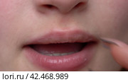 Applying moisturizer to plump lips using finger with long manicured nails before applying lipstick. Стоковое видео, видеограф А. А. Пирагис / Фотобанк Лори