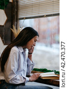 Brunette girl in a cafe drinking coffee, reading a book. Стоковое фото, фотограф Александра Баранова / Фотобанк Лори
