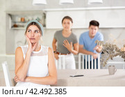 Disillusioned mother sitting in kitchen on background of dissatisfied son with wife. Стоковое фото, фотограф Яков Филимонов / Фотобанк Лори