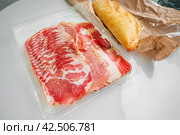 ham and flavor spices, thinly sliced on a white table with bread. close up. Стоковое фото, фотограф Оксана Медведева / Фотобанк Лори