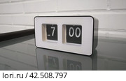 Перекидной циферблат часов будильника. Монтаж двух планов. Flip clock mechanism. 7:00 PM. Flip clock watch face. White brick wall in the background. Slow motion 240 fps. Стоковое видео, видеограф EStarodubov / Фотобанк Лори
