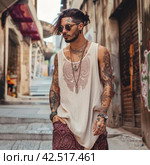 Stylish man on the street in rustic oversize thin fabric beige tank top with subtle burgundy paisley details,    Generative AI. Стоковое AI-изображение, AI-художник Анна Кривицкая / Фотобанк Лори