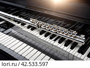 Flute with piano. Flute on piano keys. Wind instrument for musical design of concert creativity. Стоковое AI-изображение, AI-художник Aleksandr Golubev / Фотобанк Лори