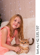 A girl is holding a beautiful cat in her arms.Девочка держит на руках красивого кота. Ребенок и домашний любимчик, питомец. Стоковое фото, фотограф Мария / Фотобанк Лори