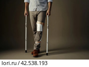 Dependent Man injured leg using crutches. Generate Ai. Стоковое AI-изображение, AI-художник Иван Рябоконь / Фотобанк Лори