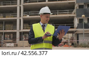 European architect in workwear and white hardhat with laptop in hands standing on building site. Стоковое видео, видеограф Яков Филимонов / Фотобанк Лори