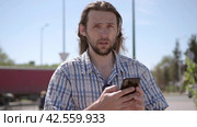 Stunned news has confused a man who walks down the street and checks the chat content of his smart phone. Стоковое видео, видеограф EStarodubov / Фотобанк Лори