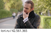 Портрет задумчивого человека, обдумывающего проблему. Portrait of a pensive man pondering a problem in a black jacket on a city street. Concept of people and emotions. Стоковое видео, видеограф EStarodubov / Фотобанк Лори