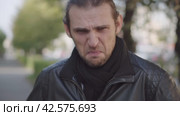 Негативное брезгливое, отвращение выражение лица. Young man in black jacket expressing disgust and disapproval with negative facial expressions outdoors. Стоковое видео, видеограф EStarodubov / Фотобанк Лори