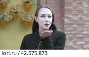 Воздушный романтический поцелуй. Mime young woman in a black coat blows romantic a kiss looking to the camera. Стоковое видео, видеограф EStarodubov / Фотобанк Лори