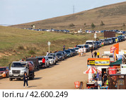 SAKHYURTA VILLAGE, BAIKAL LAKE, OLKHON ISLAND, IRKUTSK REGION, RUSSIA - August 14, 2023: A long line of autotourist cars for the ferry crossing from Olkhon Island after the summer holidays. Редакционное фото, фотограф Виктория Катьянова / Фотобанк Лори